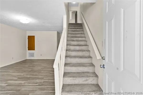 a view of staircase with wooden floor and white walls