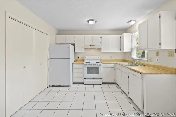 a kitchen with white cabinets a sink and white appliances