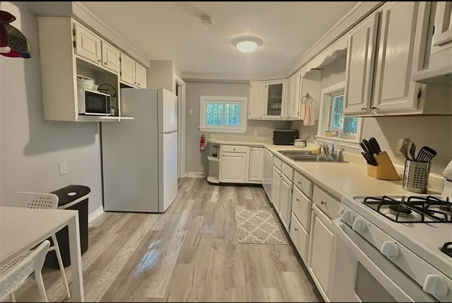 a kitchen with a sink appliances wooden floor and cabinets