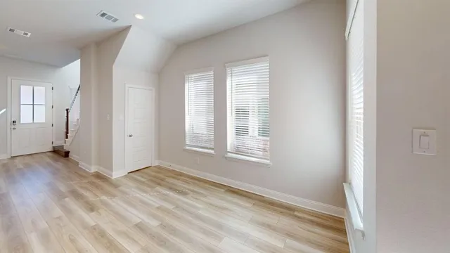 an empty room with wooden floor and windows