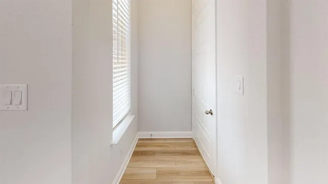 a view of a hallway with wooden floor and windows
