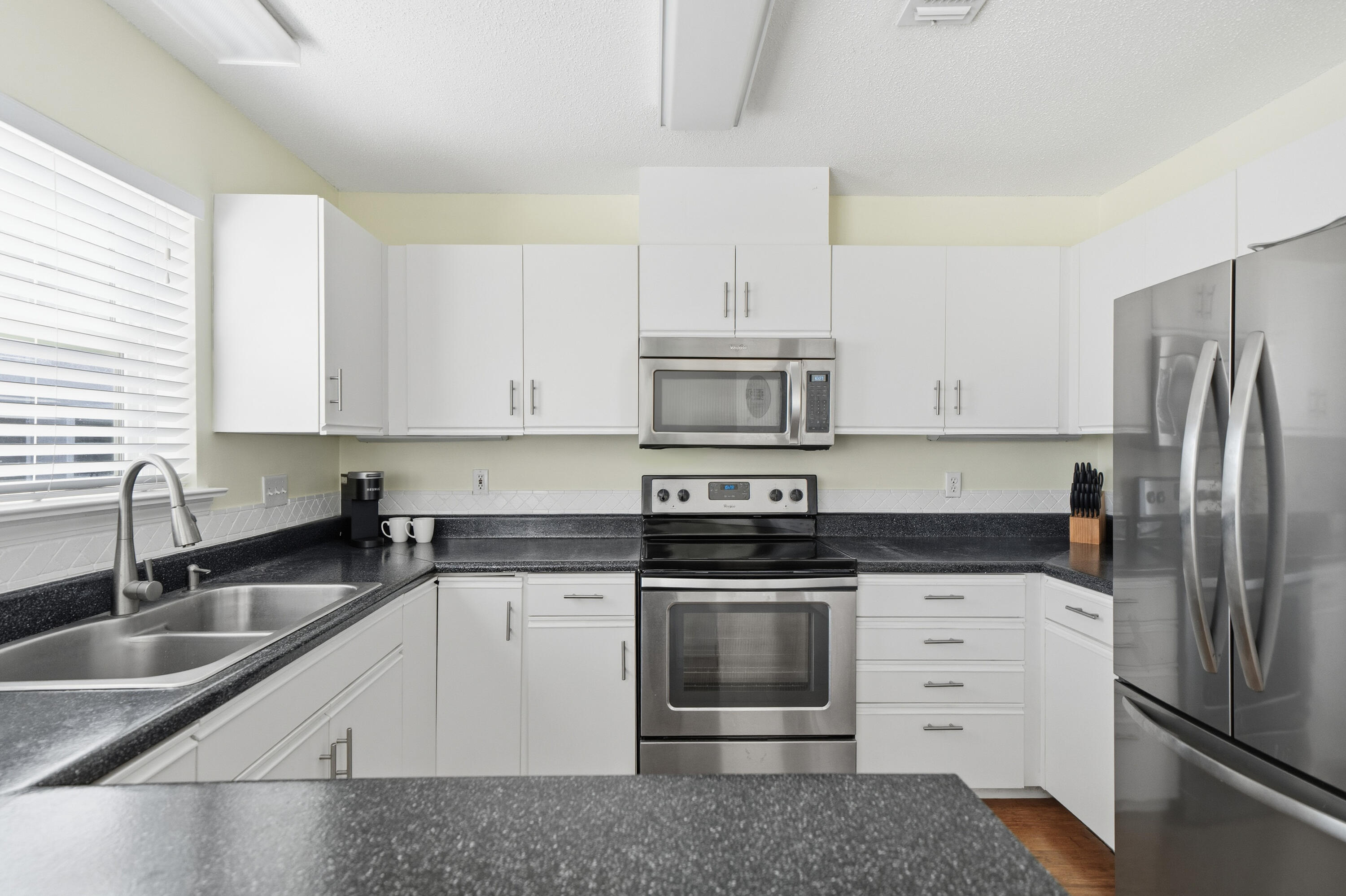 130 Durango Road, Unit 107 Destin, FL 32541 - Photo 5 of 44 a kitchen with granite countertop white cabinets and stainless steel appliances