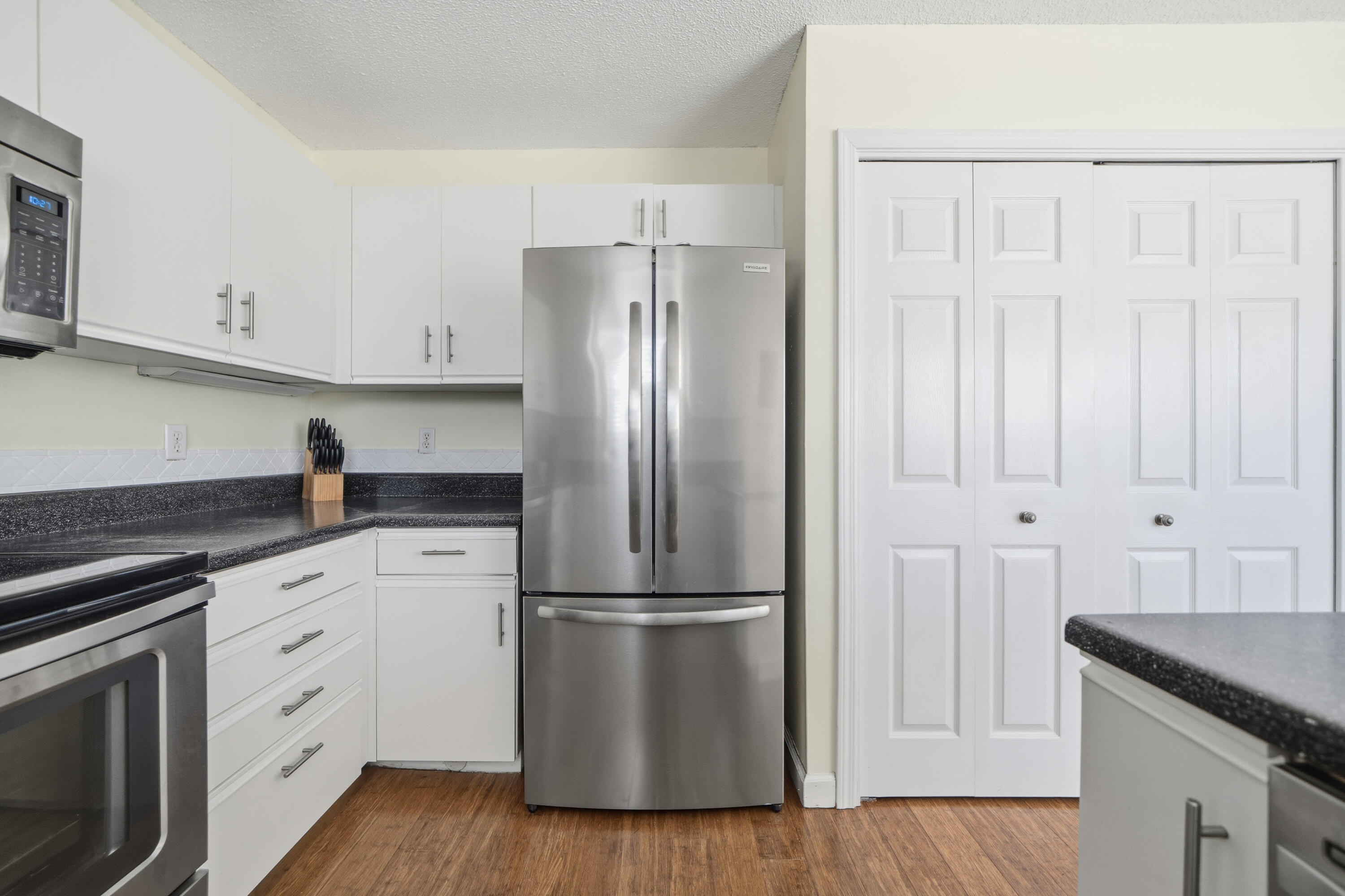 130 Durango Road, Unit 107 Destin, FL 32541 - Photo 6 of 44 a kitchen with white cabinets and stainless steel appliances