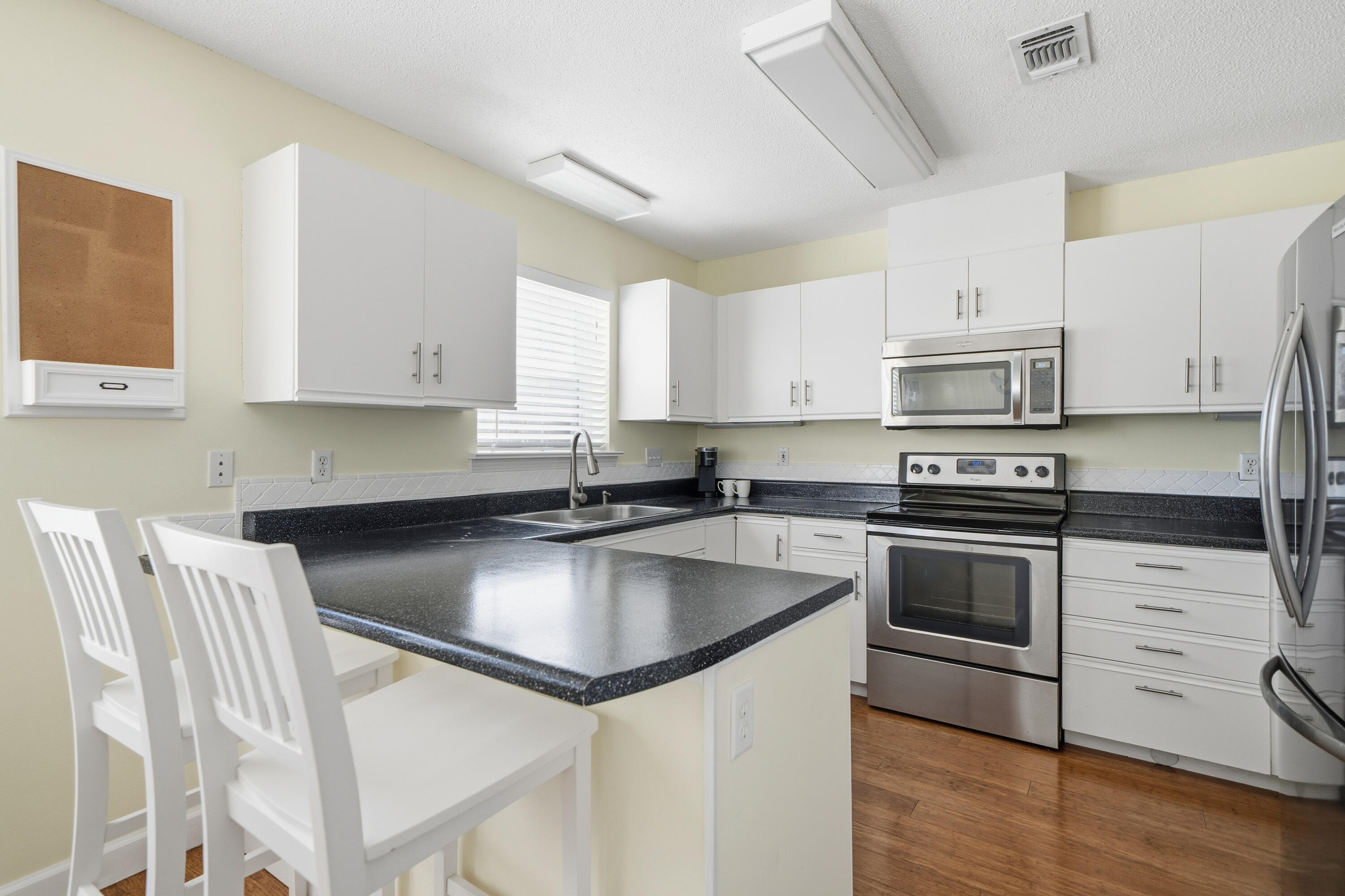 130 Durango Road, Unit 107 Destin, FL 32541 - Photo 7 of 44 a kitchen with kitchen island a stove a sink and white cabinets