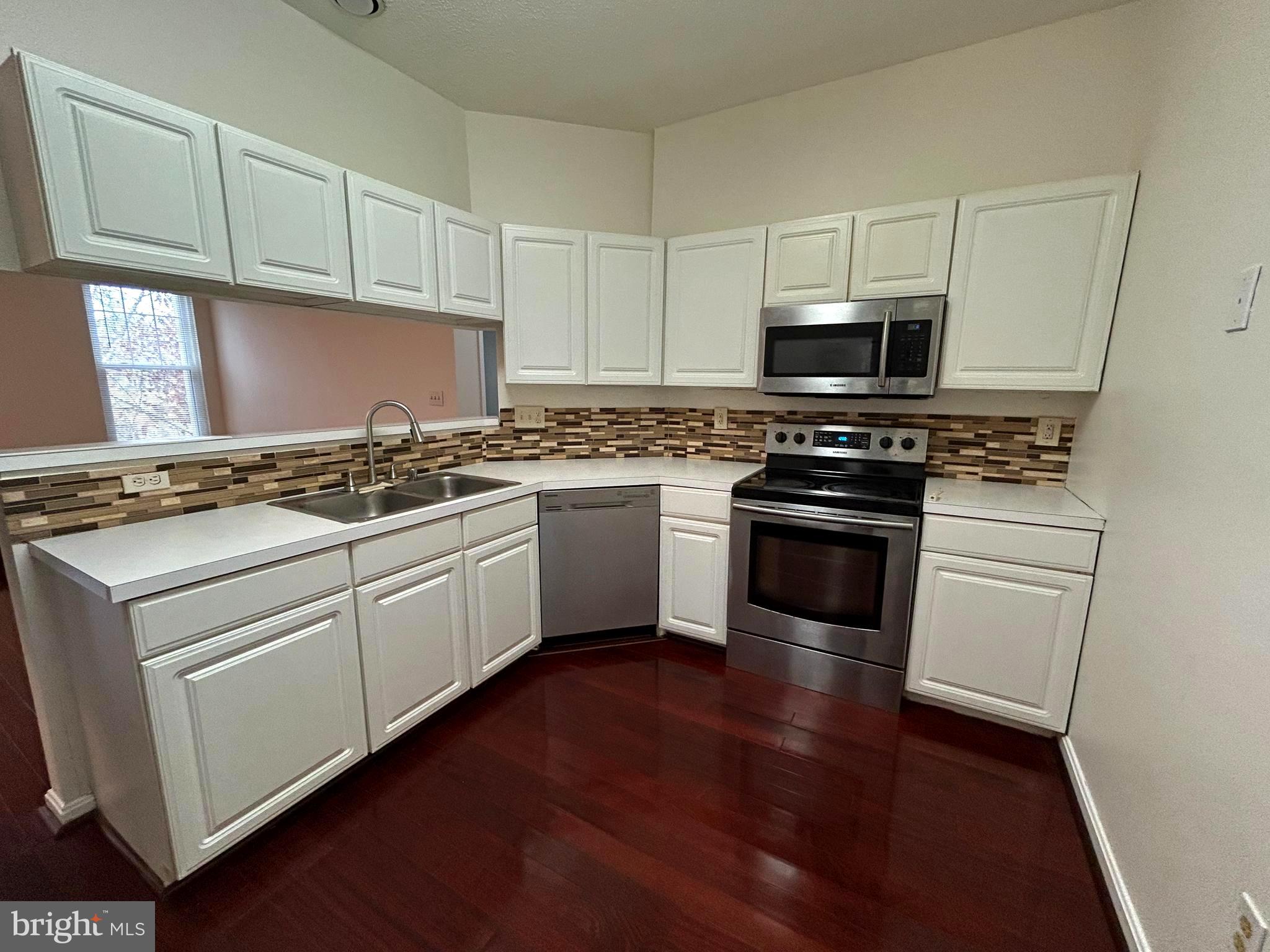 a kitchen with stainless steel appliances granite countertop a stove a sink dishwasher and a microwave oven with wooden floor