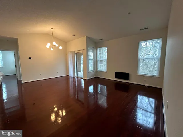 a view of a livingroom with furniture wooden floor a chandelier and windows