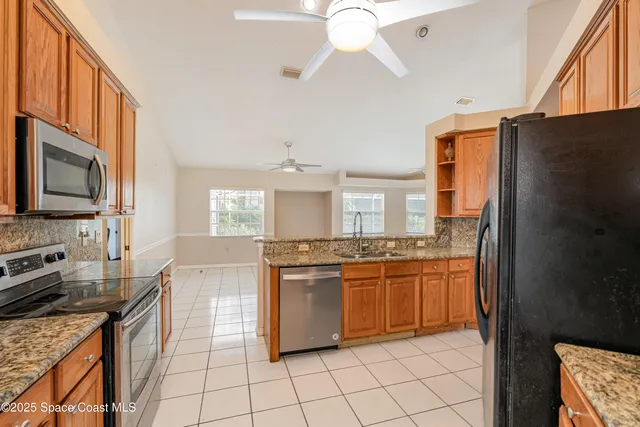 a kitchen with stainless steel appliances granite countertop a stove top oven a sink dishwasher and a refrigerator