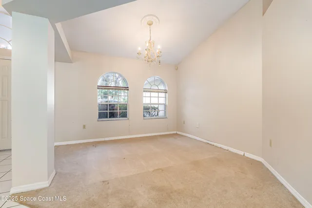an empty room with chandelier fan and windows