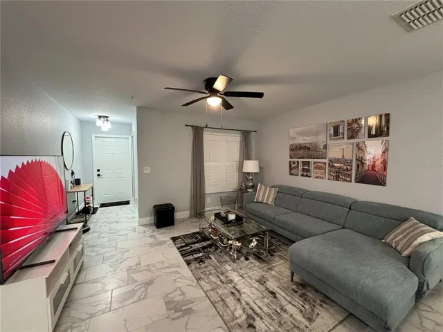 a living room with furniture a flat screen tv and kitchen view