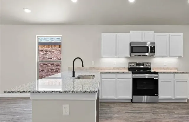 a kitchen with granite countertop a stove and a sink