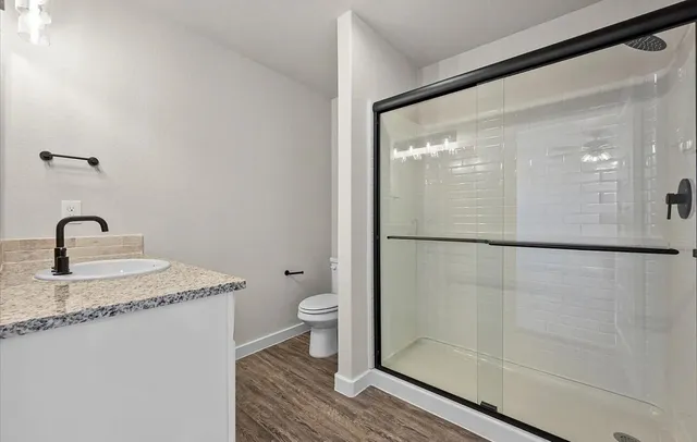 a bathroom with a granite countertop bathtub shower sink and toilet