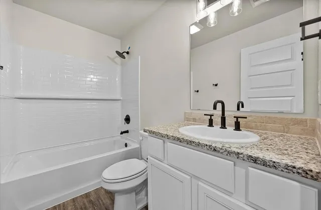 a bathroom with a granite countertop toilet sink and mirror