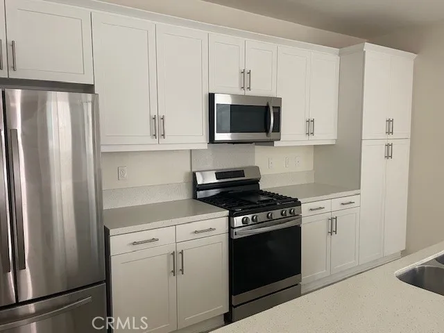 a kitchen with white cabinets and stainless steel appliances