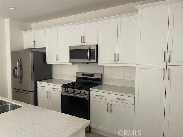 a kitchen with white cabinets and stainless steel appliances