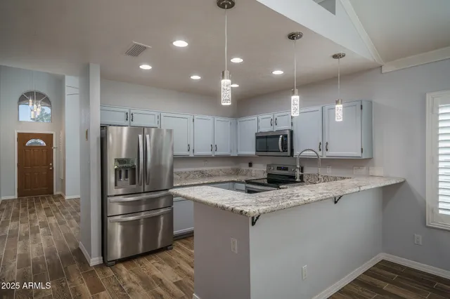 a kitchen with stainless steel appliances granite countertop a stove top oven a sink and a refrigerator