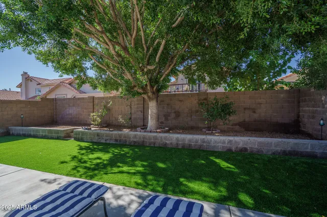 a view of a backyard with table and chairs wooden fence and plants