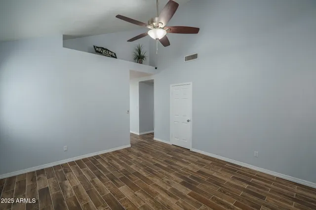 an empty room with windows fireplace and fan