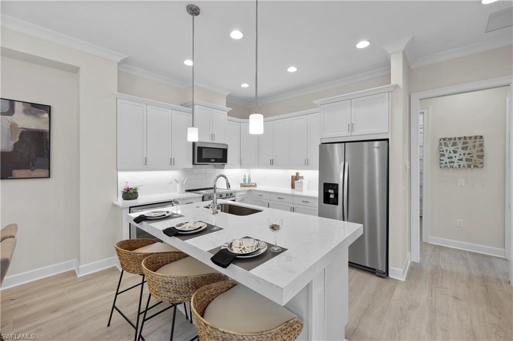 6385 Arriba Avenue Naples, FL 34113 - Photo 5 of 43 a kitchen with stainless steel appliances granite countertop a dining table chairs refrigerator and microwave