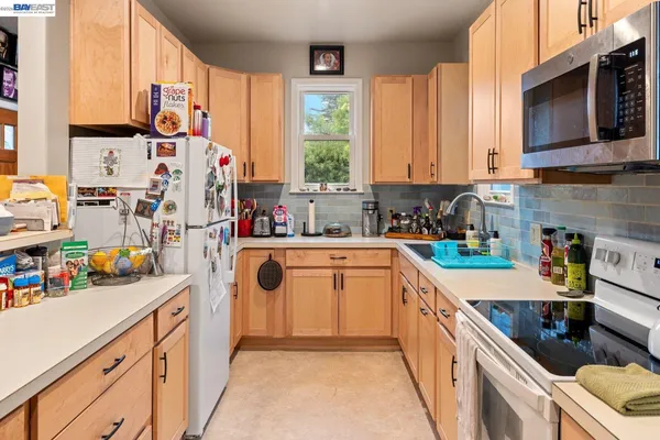 a kitchen with kitchen island granite countertop a sink dishwasher stove and white cabinets with wooden floor