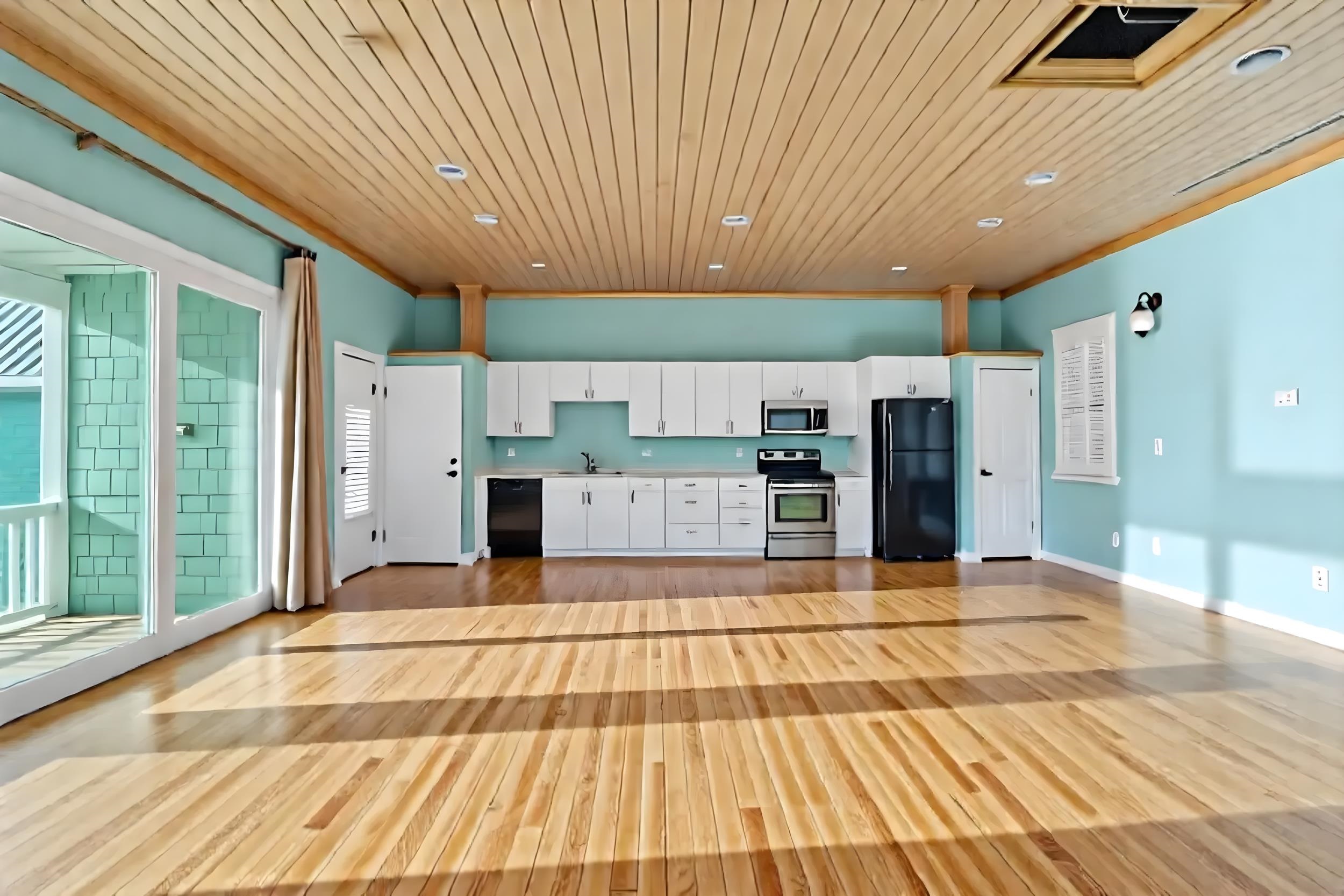 7337 A1A South St. Augustine, FL 32080 - Photo 3 of 100 Kitchen and Living Room - with white cabinets, wooden ceiling, ornamental molding, light wood finished floors, and black appliances