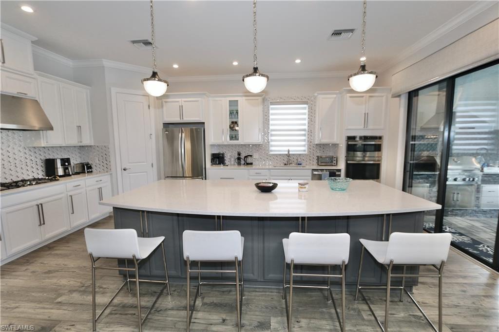 8337 Promoso Court Naples, FL 34114 - Photo 16 of 48 a kitchen with a table chairs stove and cabinets