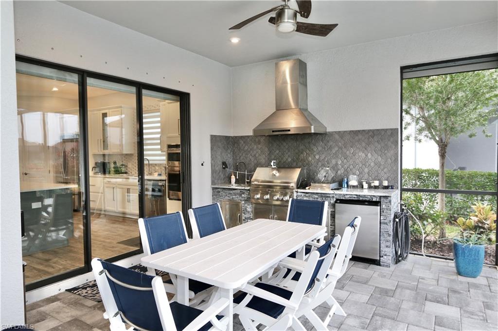 8337 Promoso Court Naples, FL 34114 - Photo 31 of 48 a kitchen with stainless steel appliances granite countertop a stove a refrigerator a sink a dining table and chairs with the wooden floor