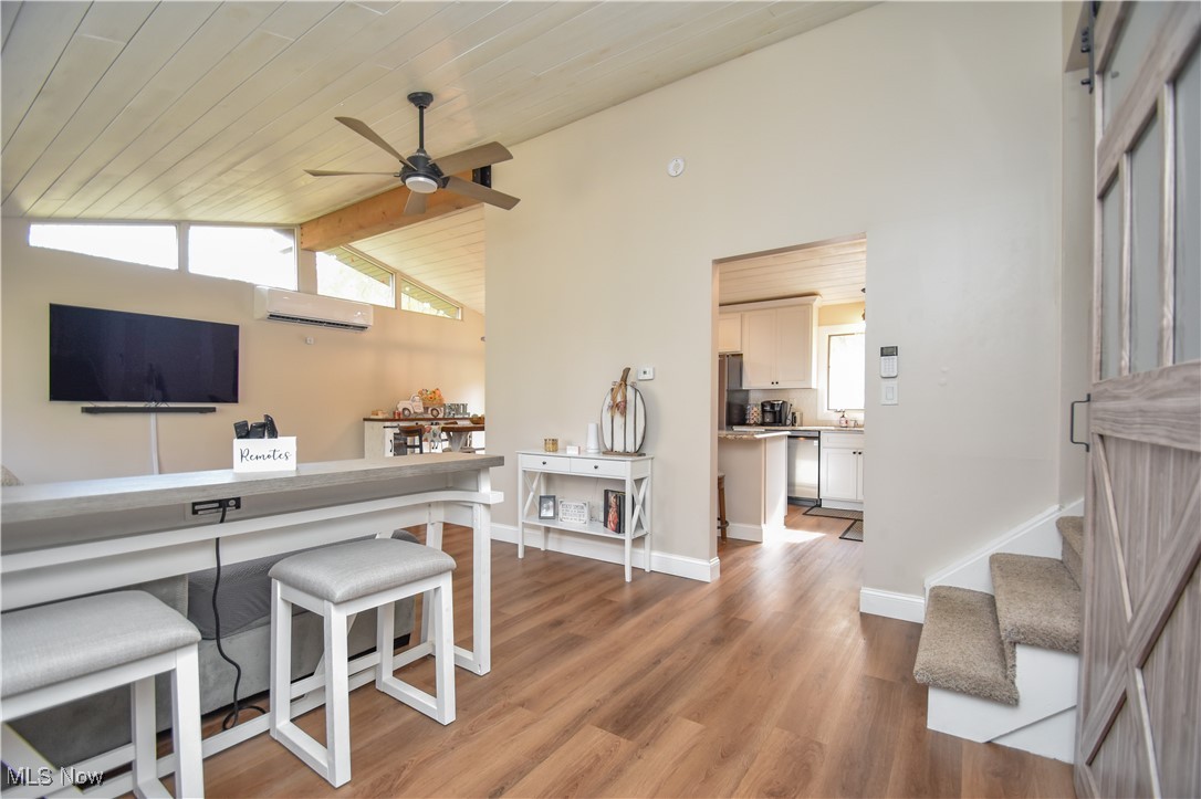 living room on main floor featuring ceiling fan, wooden ceiling, and beamed ceiling