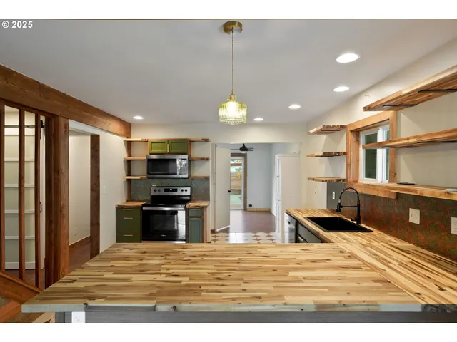 a kitchen with stainless steel appliances granite countertop a refrigerator a stove and a sink with wooden floor