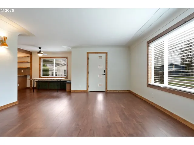a view of an empty room with a window and wooden floor