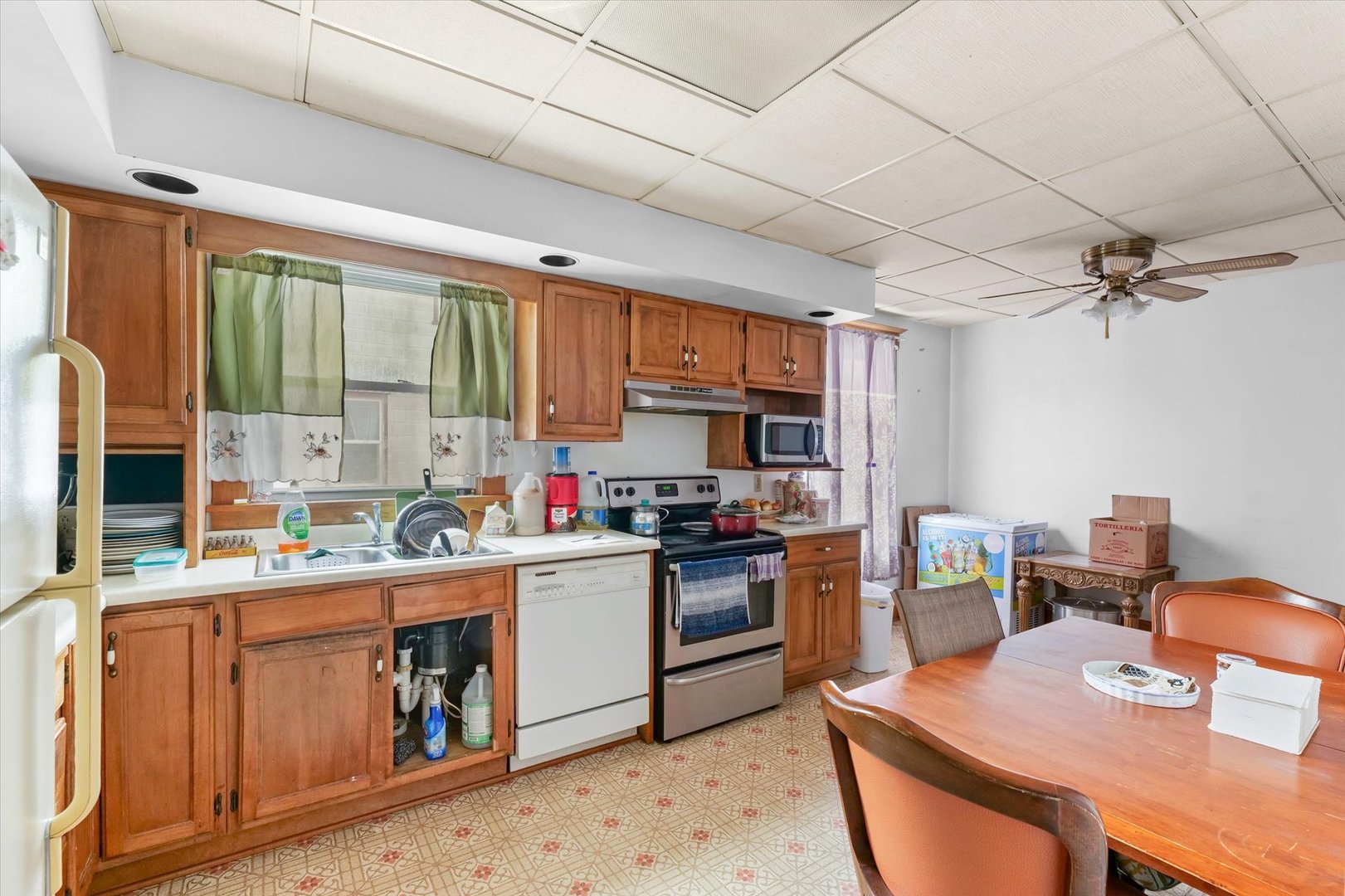 209 North Green Street Melvin, IL 60952 - Photo 9 of 24 a kitchen with stainless steel appliances granite countertop a stove top oven a sink dishwasher a dining table and chairs with wooden floor