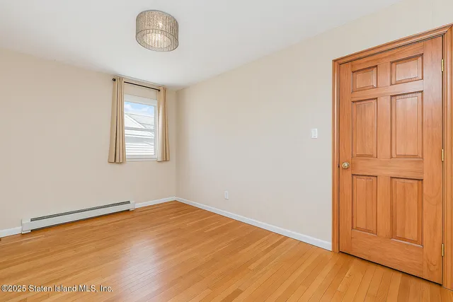 an empty room with wooden floor cabinet and windows