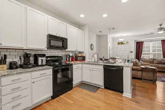 a kitchen with stainless steel appliances granite countertop a sink dishwasher stove top oven and cabinets with wooden floor