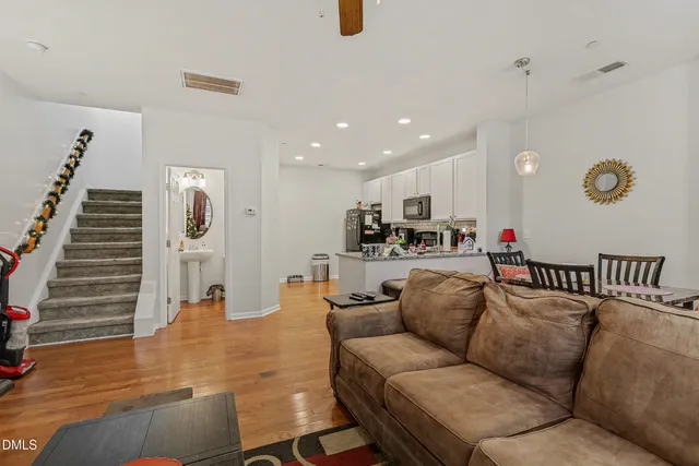 a living room with furniture kitchen view and a wooden floor