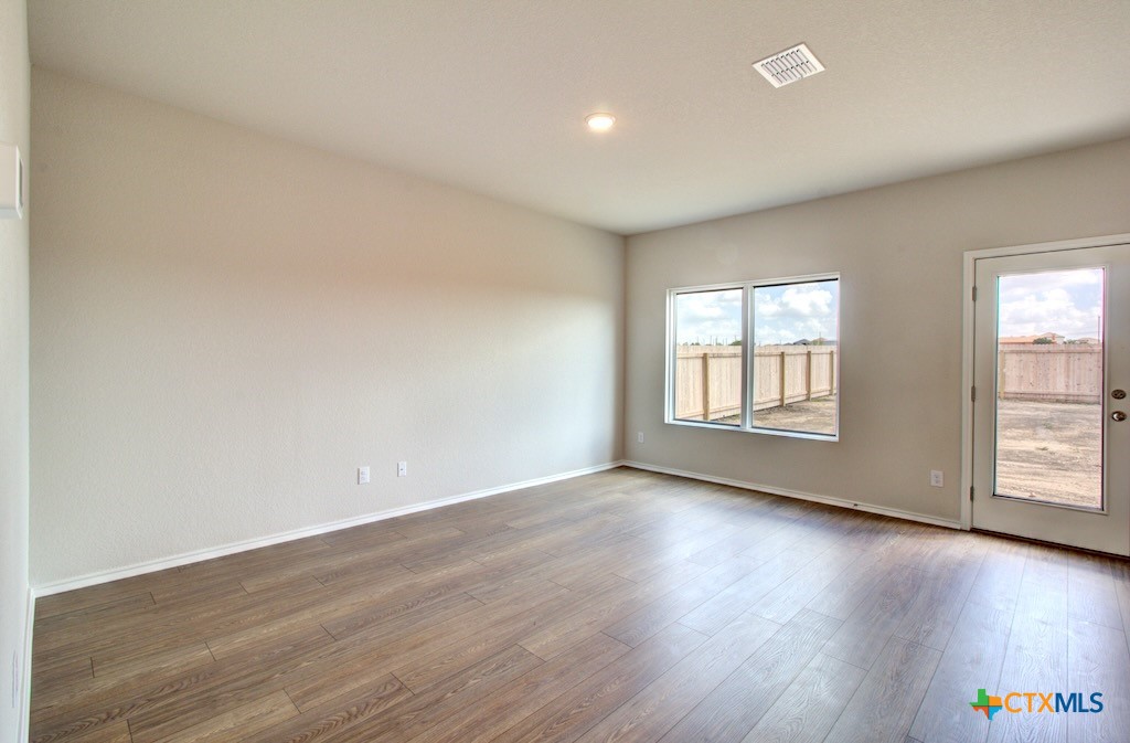 11242 Prairie Landing Converse, TX 78109 - Photo 5 of 24 an empty room with wooden floor and windows with curtains