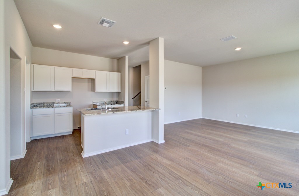 11242 Prairie Landing Converse, TX 78109 - Photo 8 of 24 a kitchen with wooden floors white cabinets and stainless steel appliances
