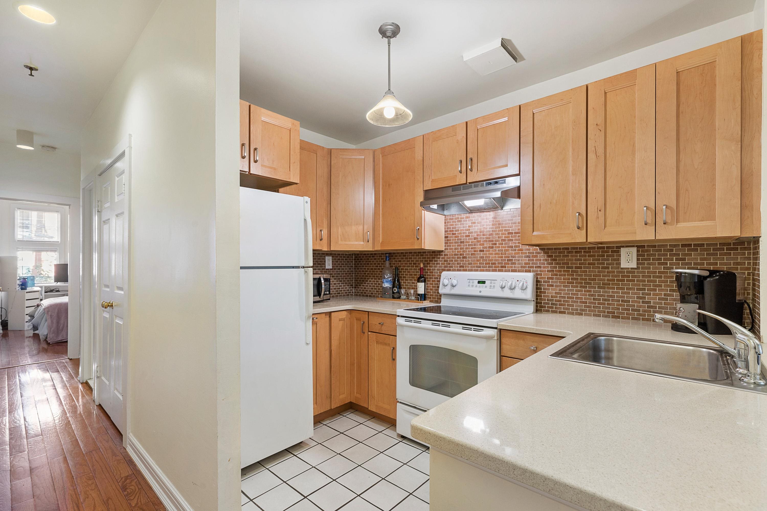 73 Madison Street, Unit 1N Hoboken, NJ 07030 - Photo 11 of 17 a kitchen with stainless steel appliances granite countertop a refrigerator a sink dishwasher a stove with white cabinets