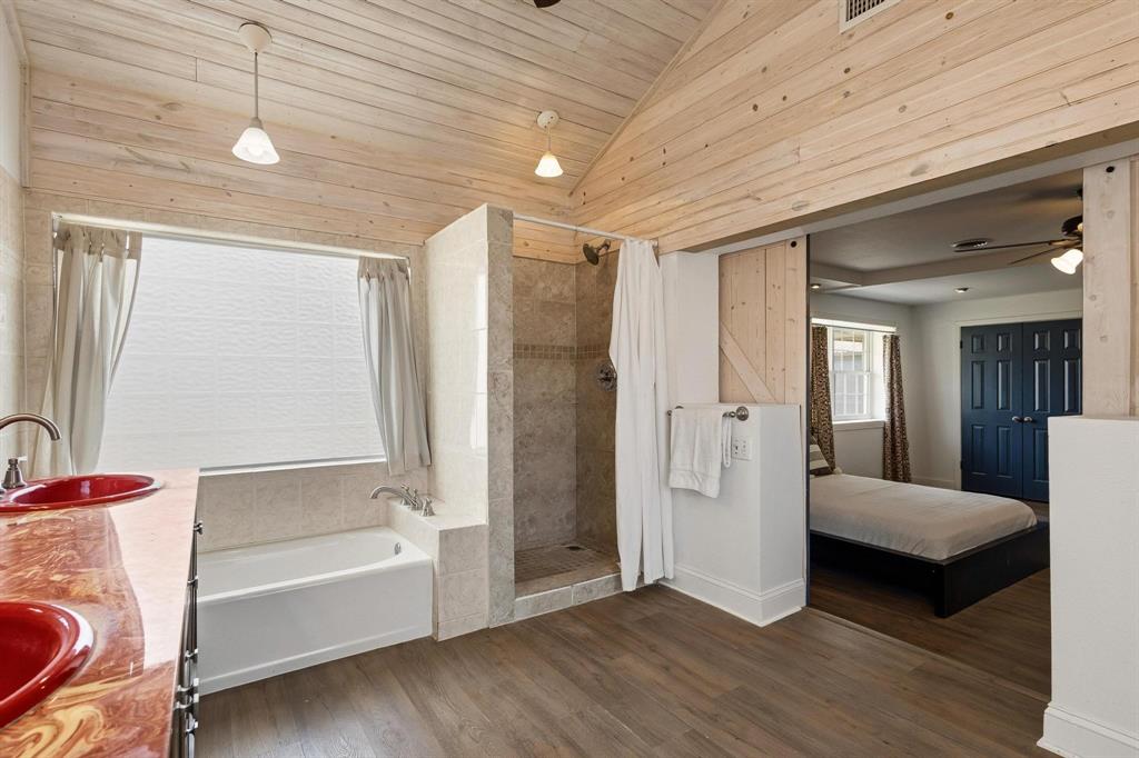 1053 Paradise Cove Road Pottsboro, TX 75076 - Photo 13 of 35 Primary ensuite bathroom with double vanity, dark wood-type flooring, a garden tub, a shower stall, and a vaulted wood ceiling