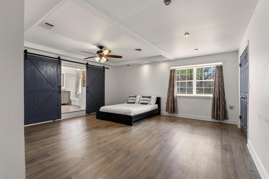 1053 Paradise Cove Road Pottsboro, TX 75076 - Photo 10 of 35 Bedroom with a barn door, dark wood-style flooring, a ceiling fan, and connected bathroom