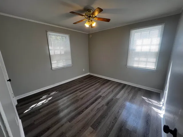 a view of empty room with wooden floor and fan