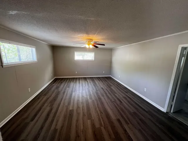 a view of empty room with wooden floor and fan