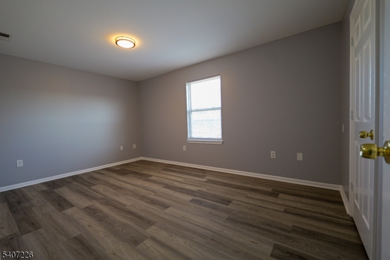 40 11th Avenue West, Unit 2 Newark, NJ 07107 - Photo 9 of 15 an empty room with wooden floor and windows