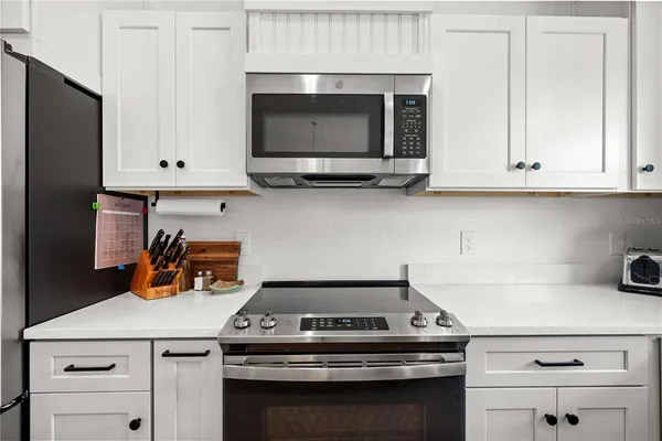 a kitchen with stainless steel appliances granite countertop a table chairs sink refrigerator and microwave