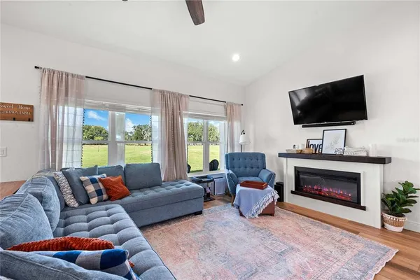 a living room with stainless steel appliances kitchen island granite countertop a sink a stove and a wooden floors