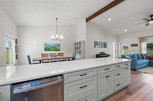 a living room with stainless steel appliances kitchen island granite countertop a sink a stove and a wooden floors