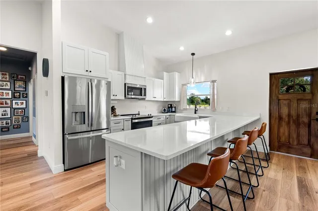 a kitchen with granite countertop a refrigerator a stove a sink and a dining table with wooden floor