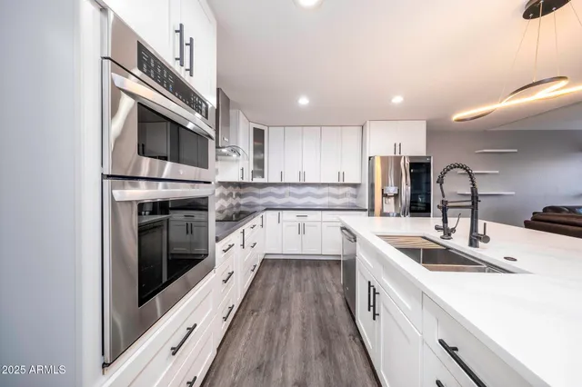 a kitchen with stainless steel appliances granite countertop a sink a stove top oven and refrigerator