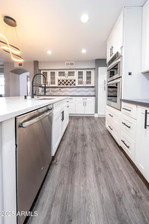 a large kitchen with stainless steel appliances granite countertop a lot of counter space and wooden floor