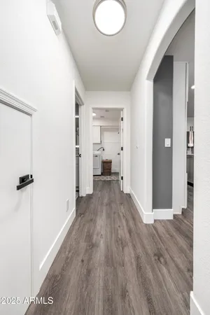 a view of a hallway with wooden floor and a bathroom