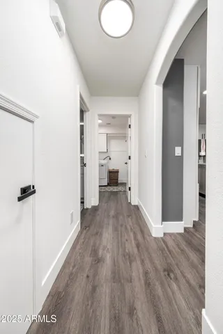 a view of a hallway with wooden floor and a bathroom