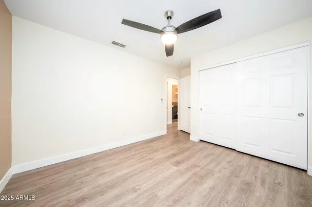 an empty room with wooden floor and ceiling fan